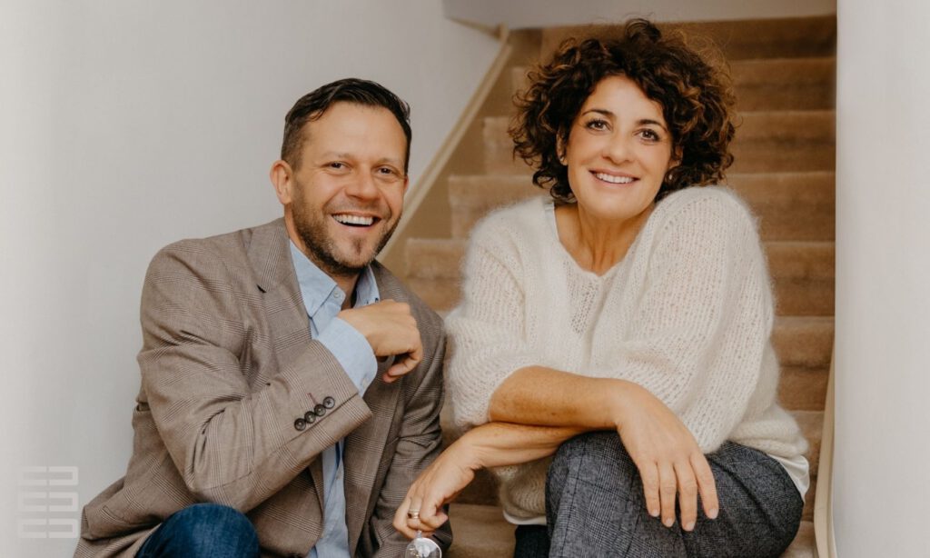 Familienmediatoren Sören Peter und Jasmin Hirnich sitzen lachend auf einer Treppe